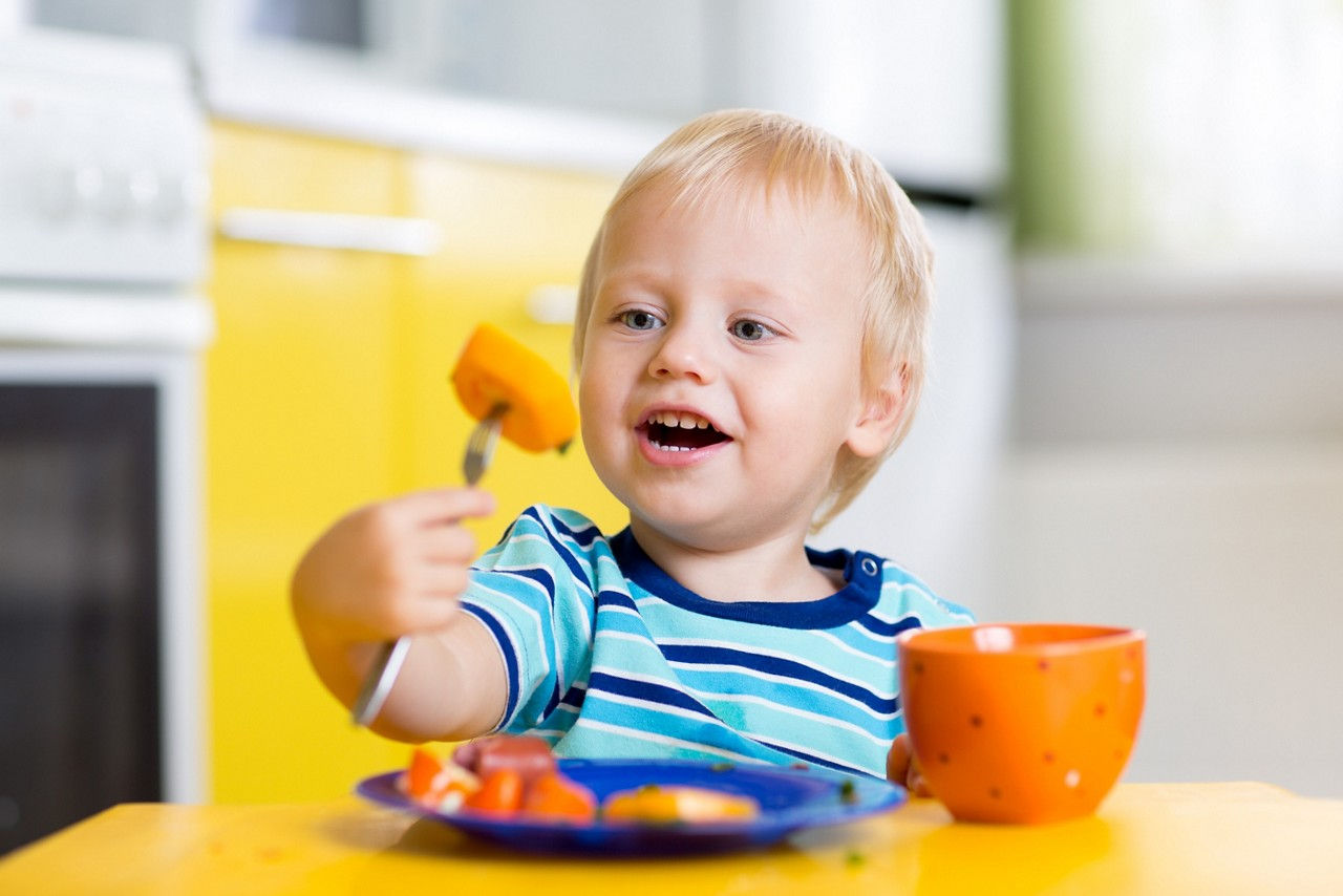 Toddler sitting at the table enjoying fruits